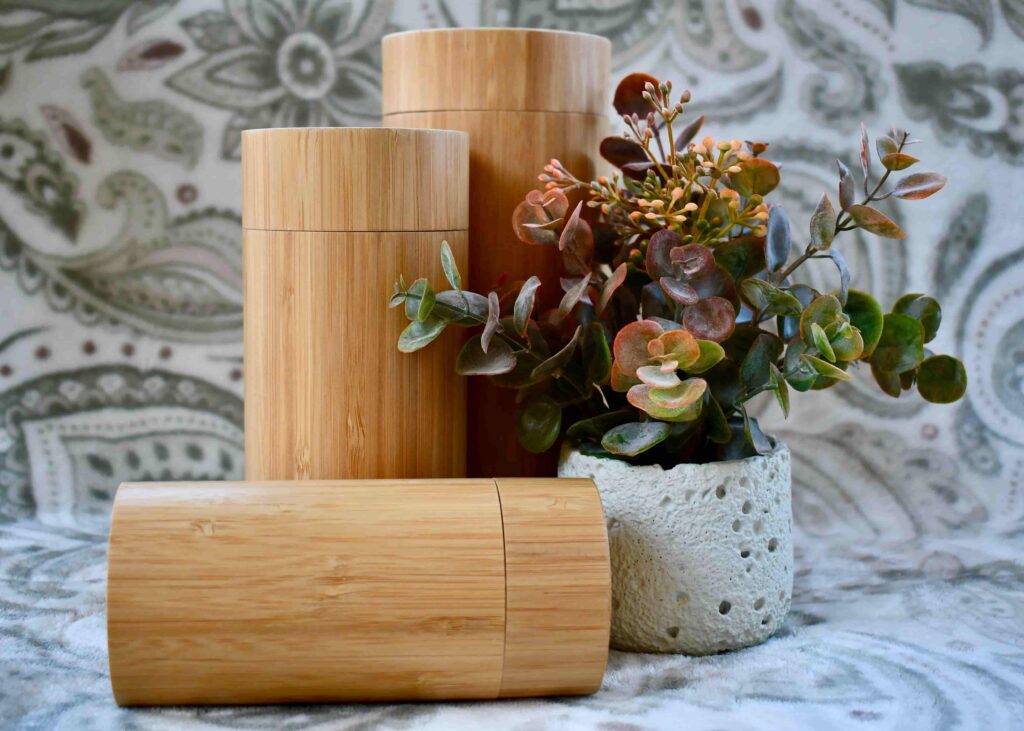 Set of three cylindrical bamboo scattering tube urns, an elegant upgrade option from Furevergreen Aquamation, displayed beside a small potted plant.